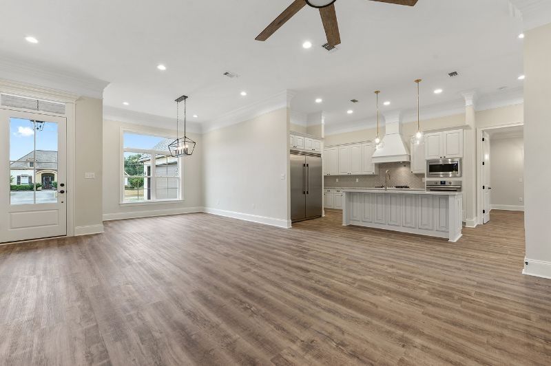 Spacious, open-concept living space with hardwood floors, kitchen, and light-filled windows and doors.