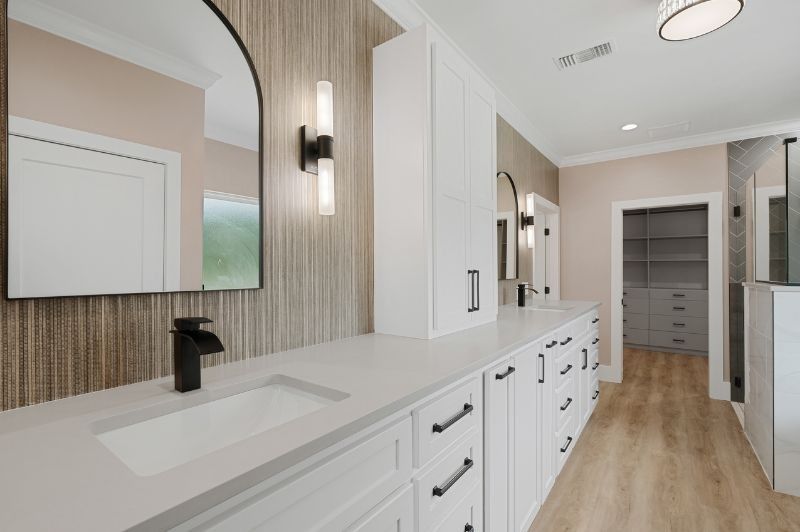 Modern bathroom with white vanity, black fixtures, arched mirror, and walk-in closet.