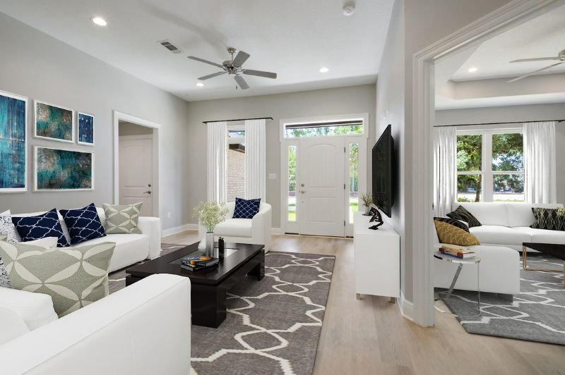 Modern living room with white furniture, gray rug, and blue art.