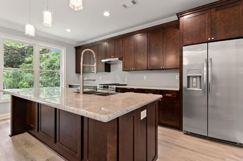 Modern kitchen with brown cabinets, stainless steel appliances, and granite island.