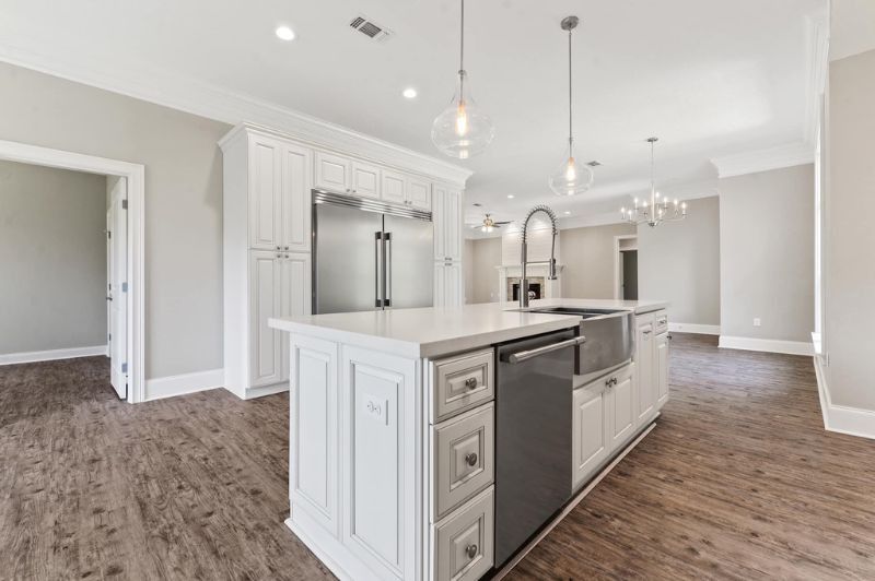 White kitchen with island, stainless steel appliances, and hardwood floors.