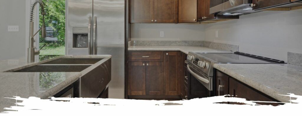A modern kitchen with dark cabinets, stainless steel appliances, and a granite countertop.