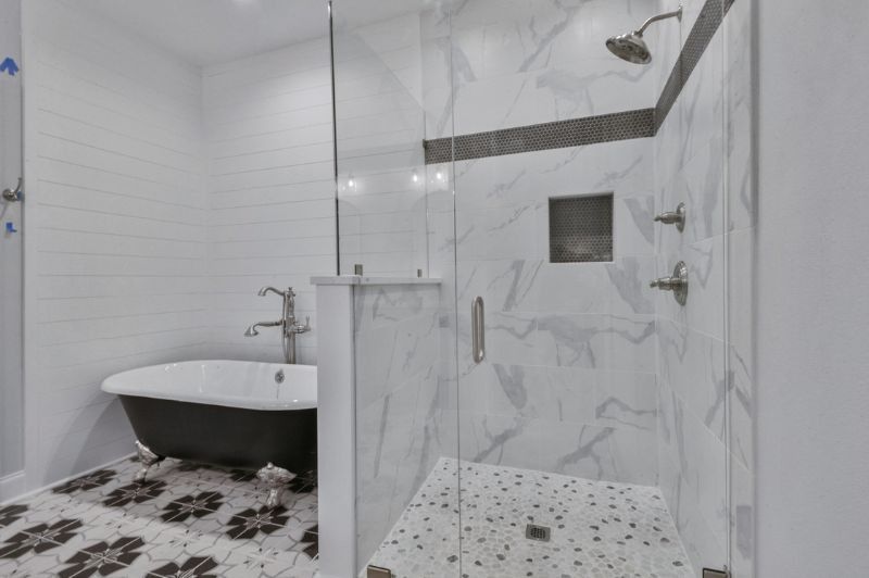 Bathroom with marble shower, clawfoot tub, and patterned floor.