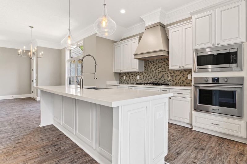 White kitchen with large island, cabinets, and stainless steel appliances.