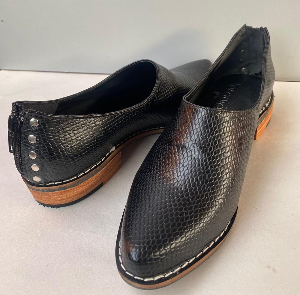 Un par de zapatos negros sobre una superficie blanca