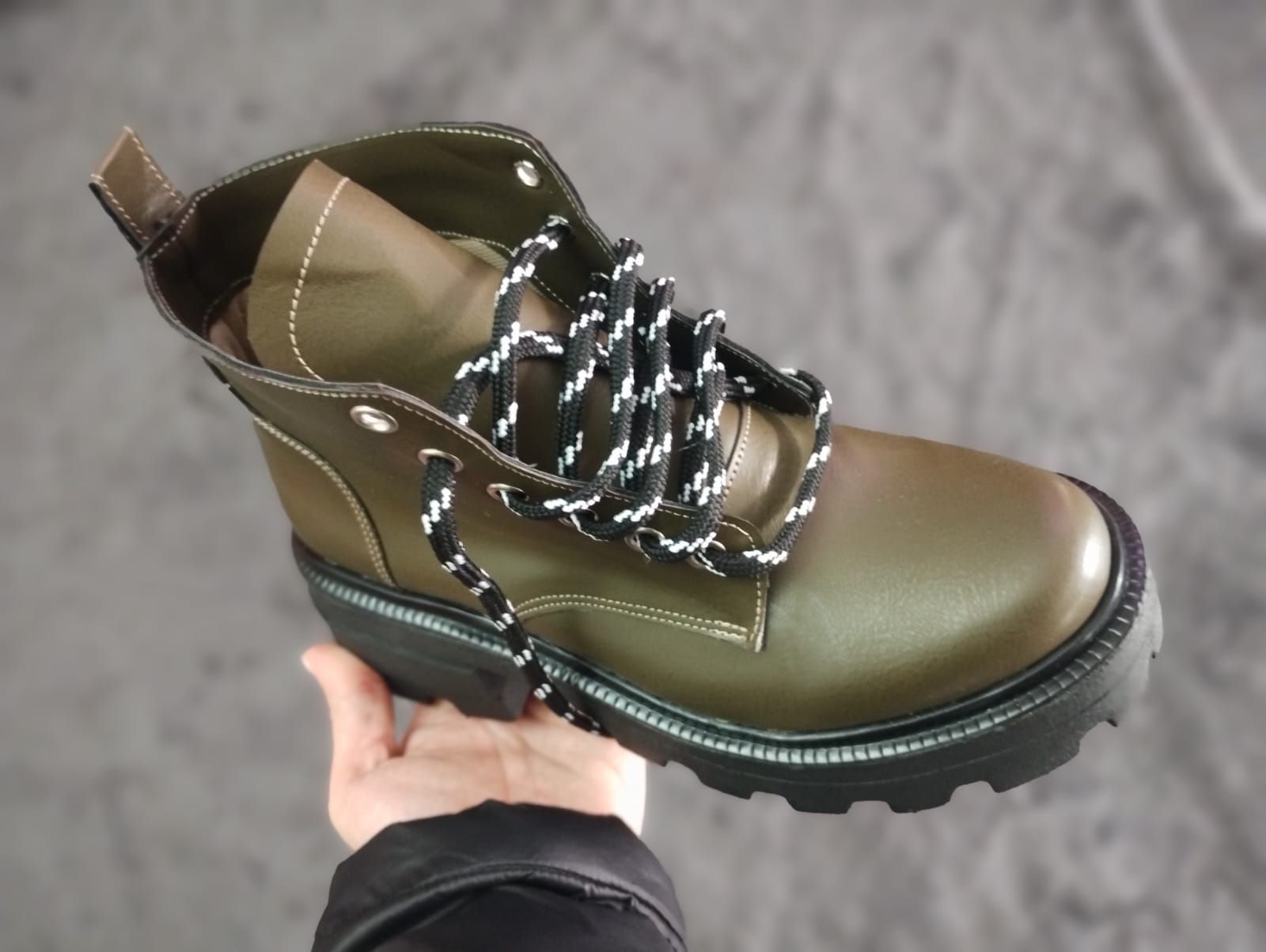 Un par de botas negras están colocadas encima de una alfombra gris.