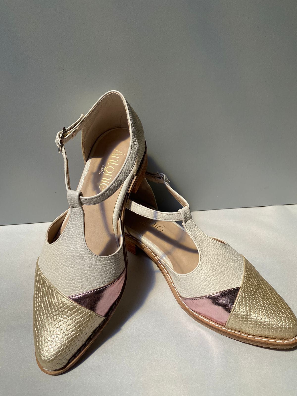 Un par de zapatos dorados y blancos están sobre una mesa.