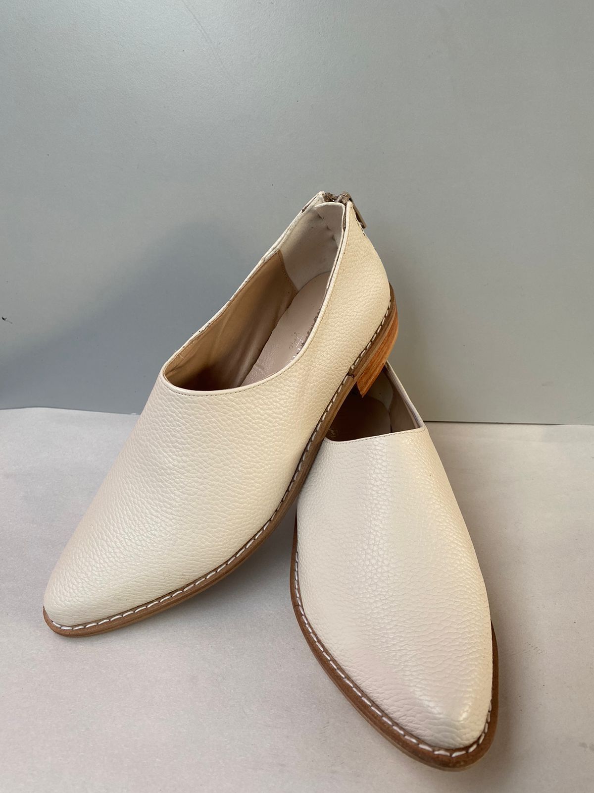 Un par de zapatos blancos están sobre una superficie blanca.