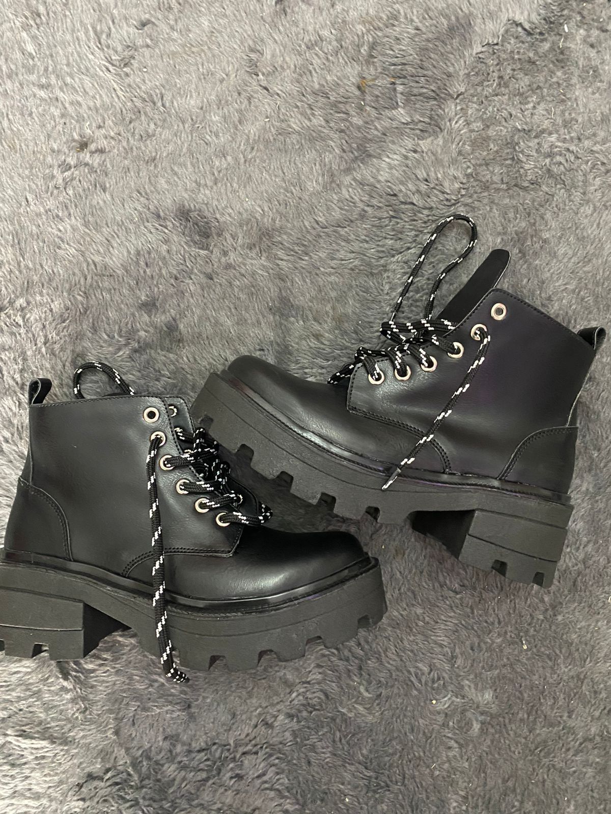 Un par de botas negras están colocadas encima de una alfombra gris.