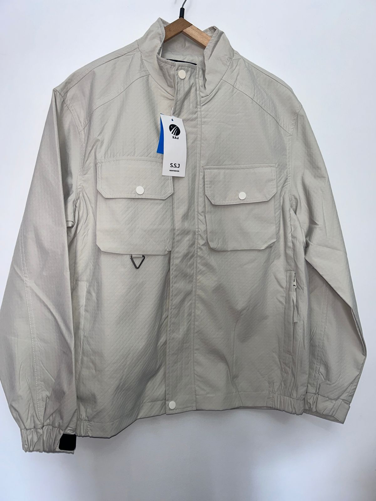 Una chaqueta beige con una etiqueta está colgada en una percha.