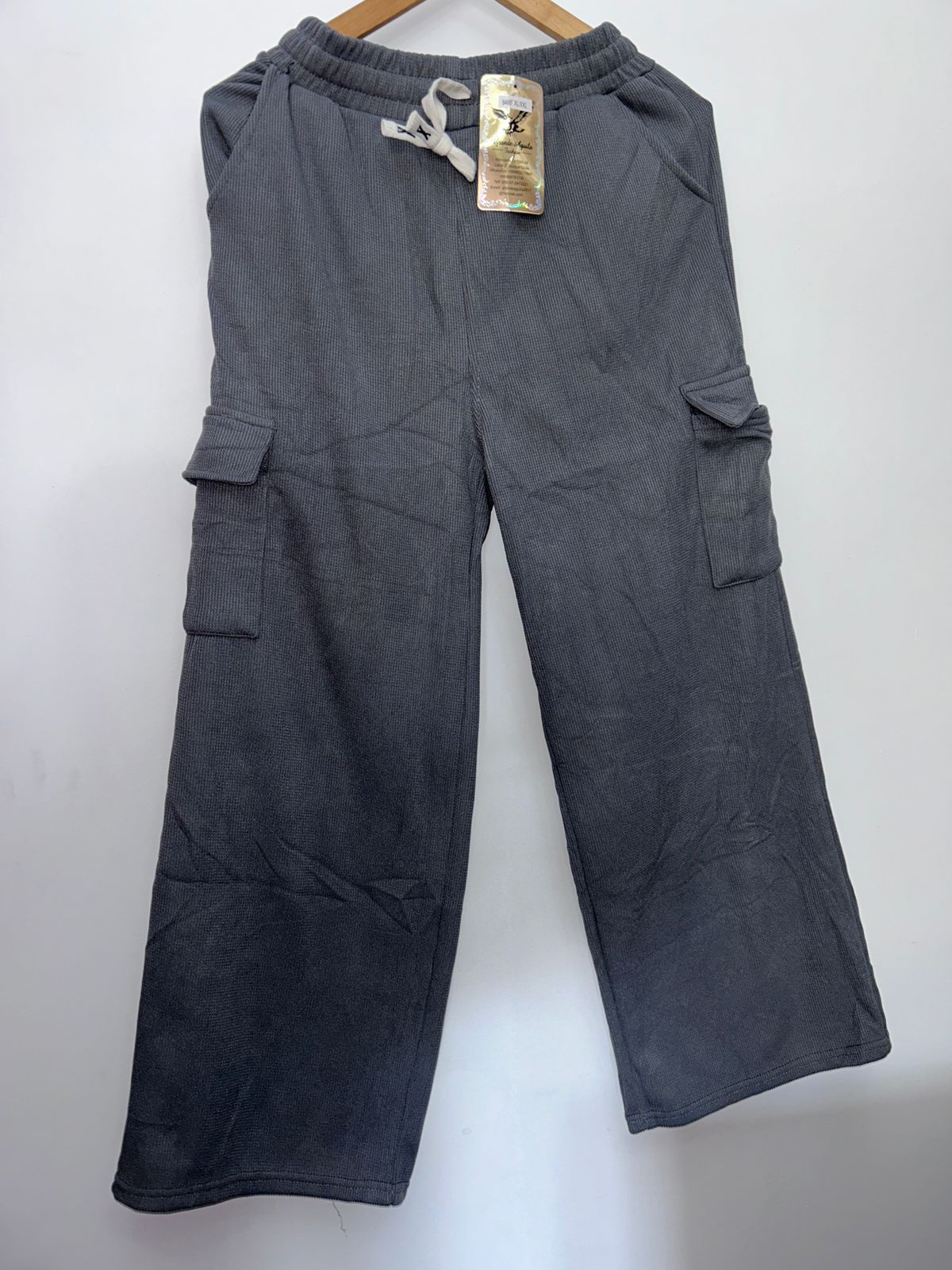 Un par de pantalones cargo grises con una etiqueta colgando de una percha.