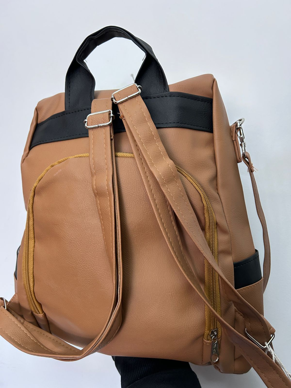 La parte trasera de una mochila marrón con una correa negra.