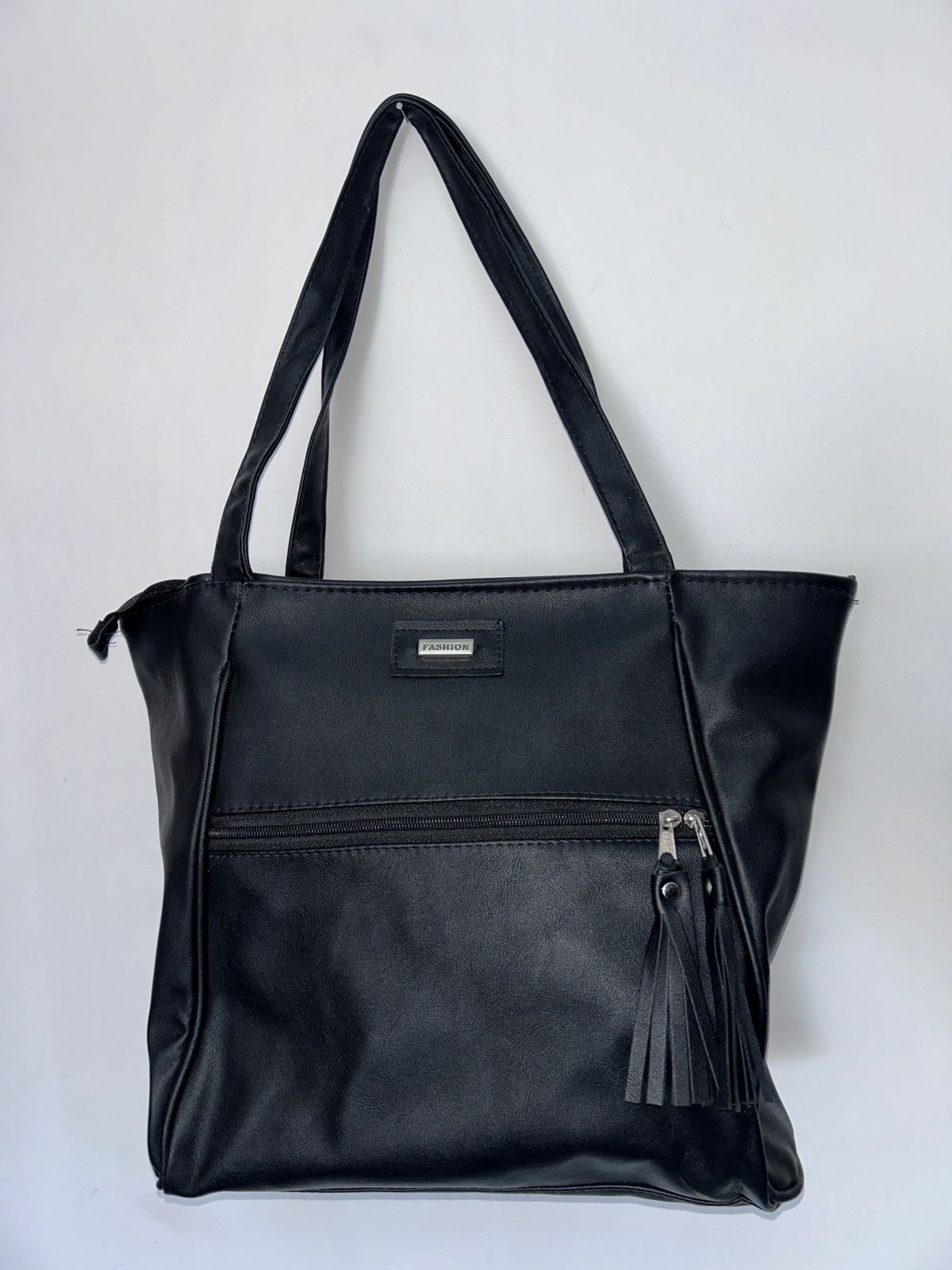 Un bolso de mano negro con una borla en el lateral.