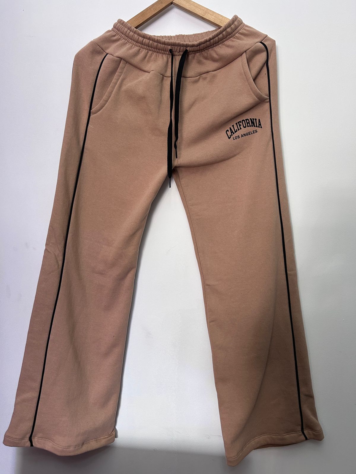 Un par de pantalones deportivos marrones colgados en una percha de madera.