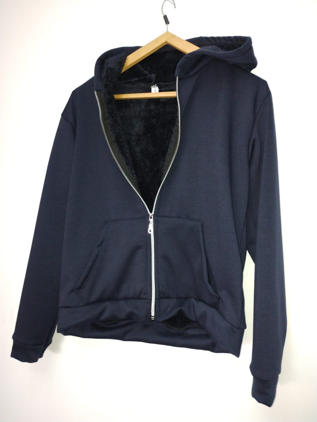 Una sudadera con capucha negra está colgada en una percha de madera.