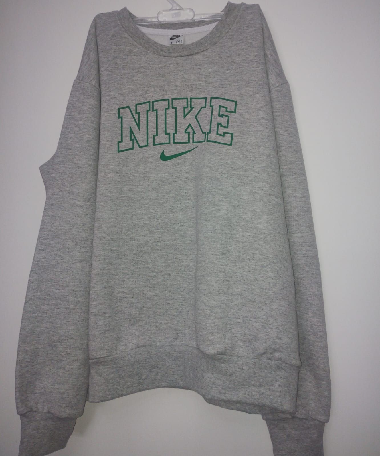 Una sudadera Nike gris está colgada en una percha.