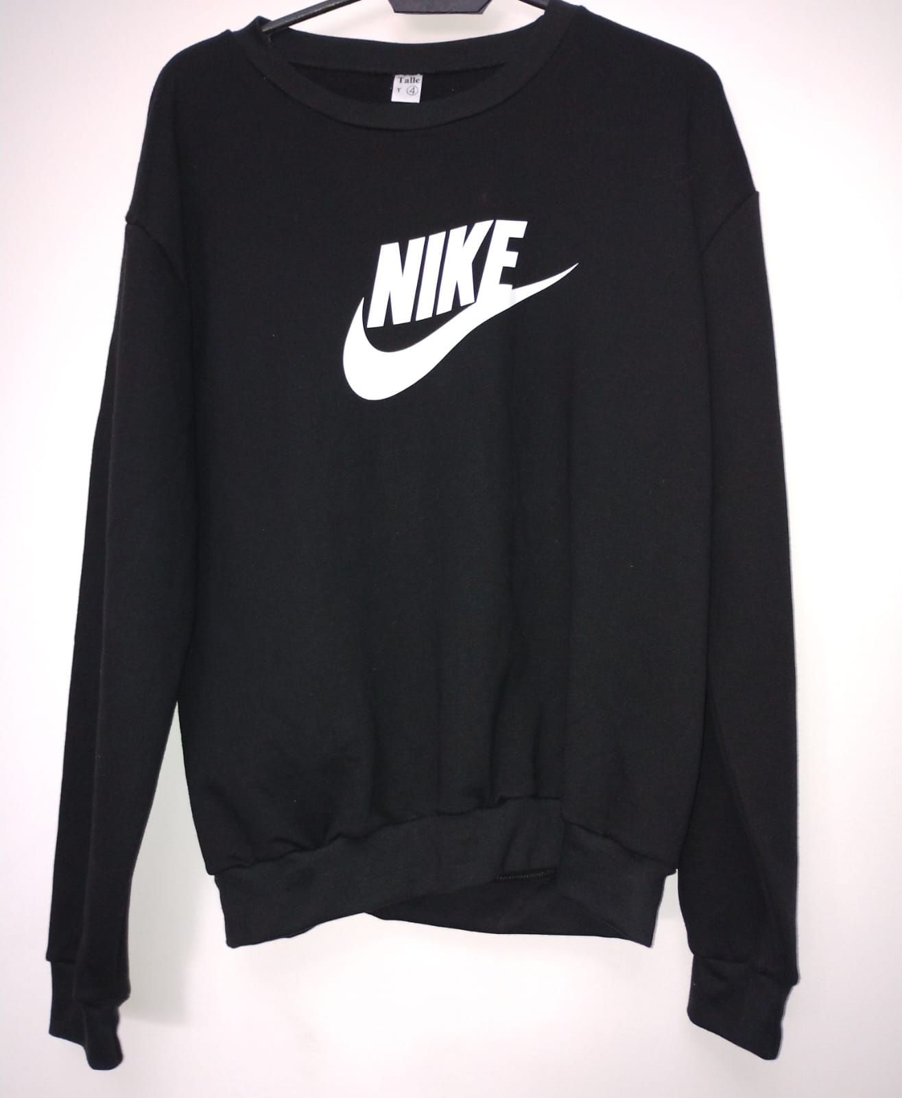 Una sudadera Nike negra está colgada en una percha.
