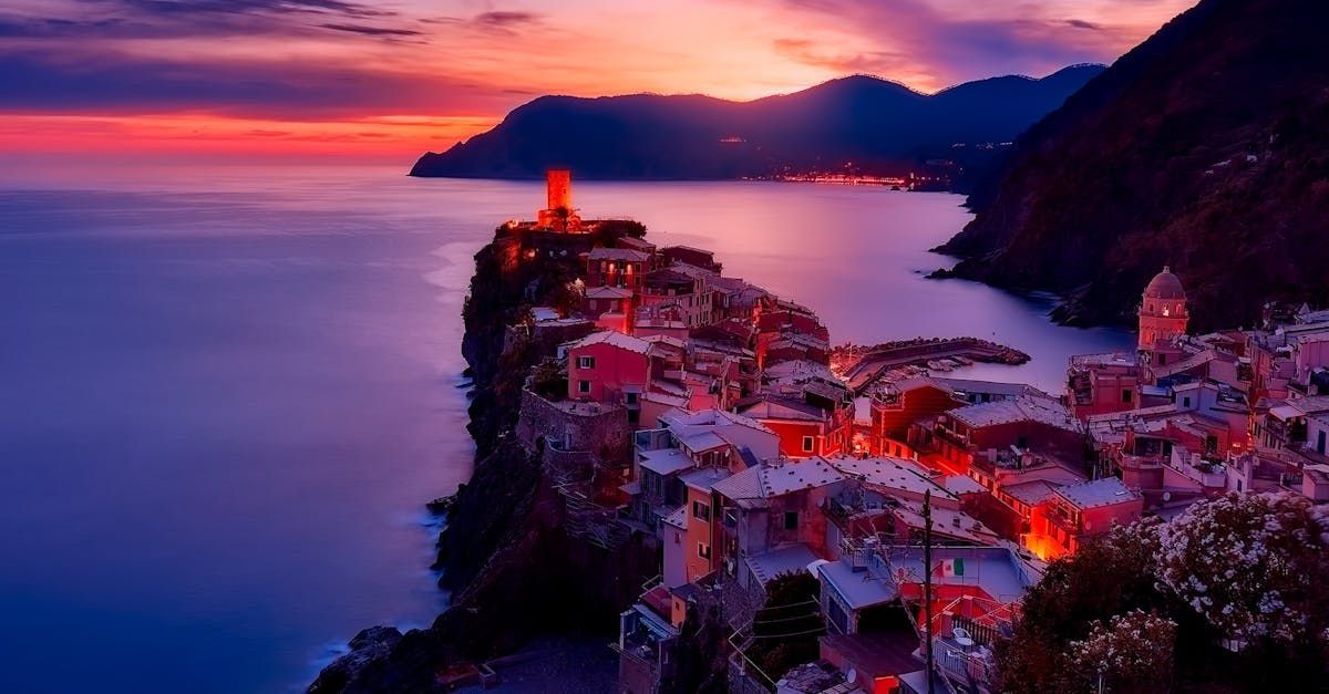 Coastal town at sunset with colorful buildings and water.