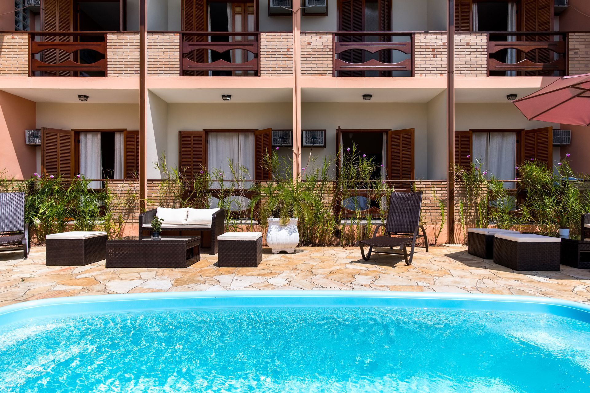 Uma piscina em frente a um prédio com cadeiras e guarda-sóis.