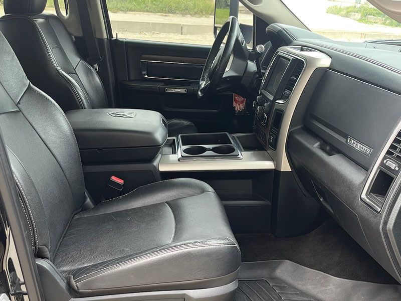 Black leather interior of a truck, featuring seats, dashboard, and center console with cup holders.