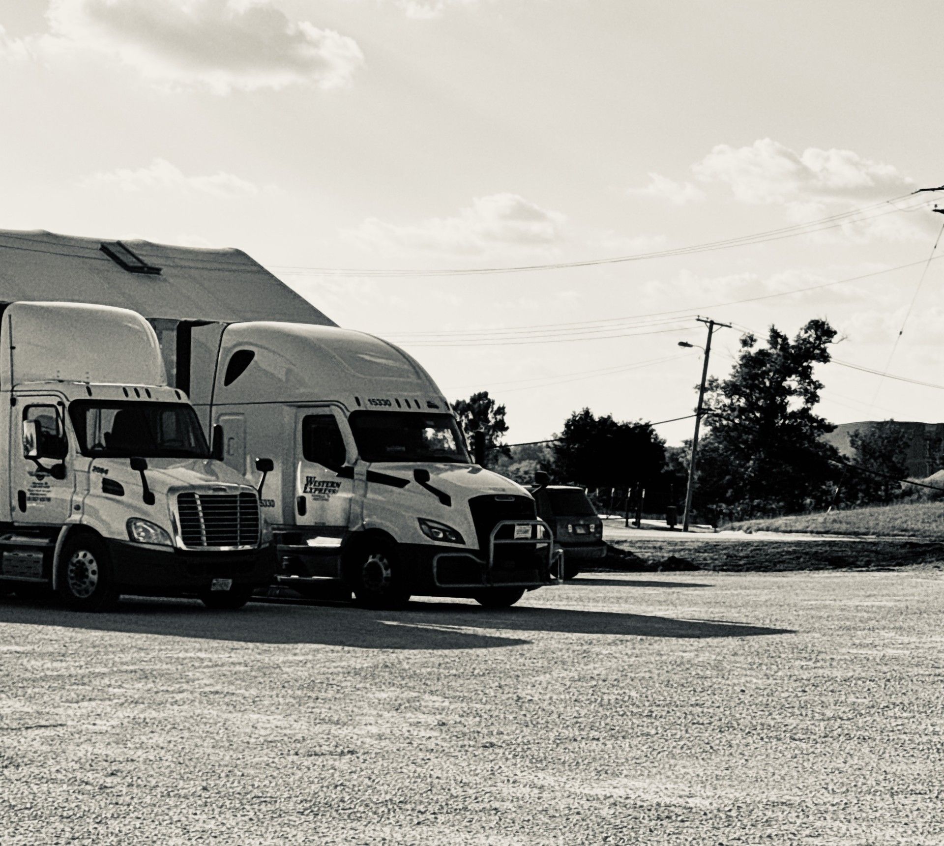 Mechanic working on the side of a white truck in a garage; sunlight shines from open bay door.