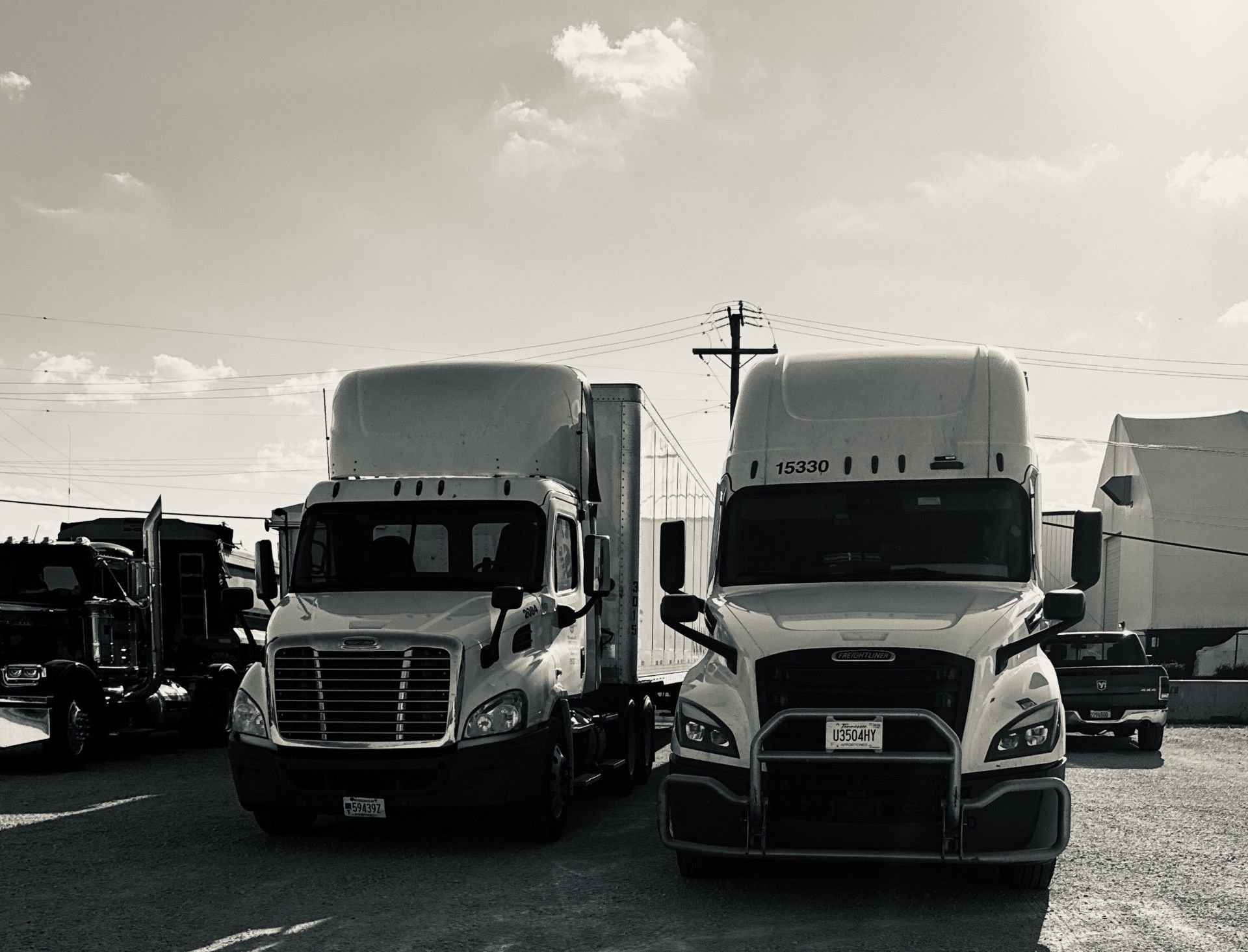 Two semi-trucks parked outdoors on a sunny day.