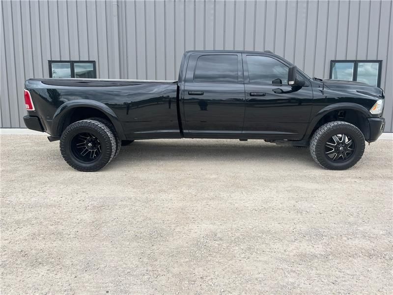 Black Ram pickup truck parked outside a building, black wheels, tinted windows.