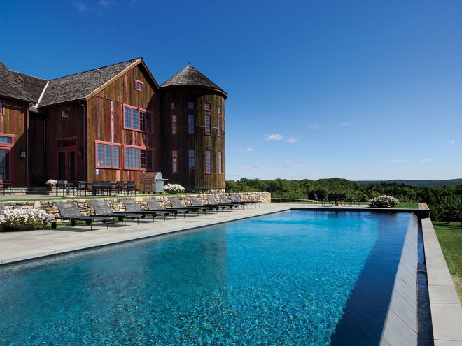 A man is standing next to a pile of wood in a workshop.