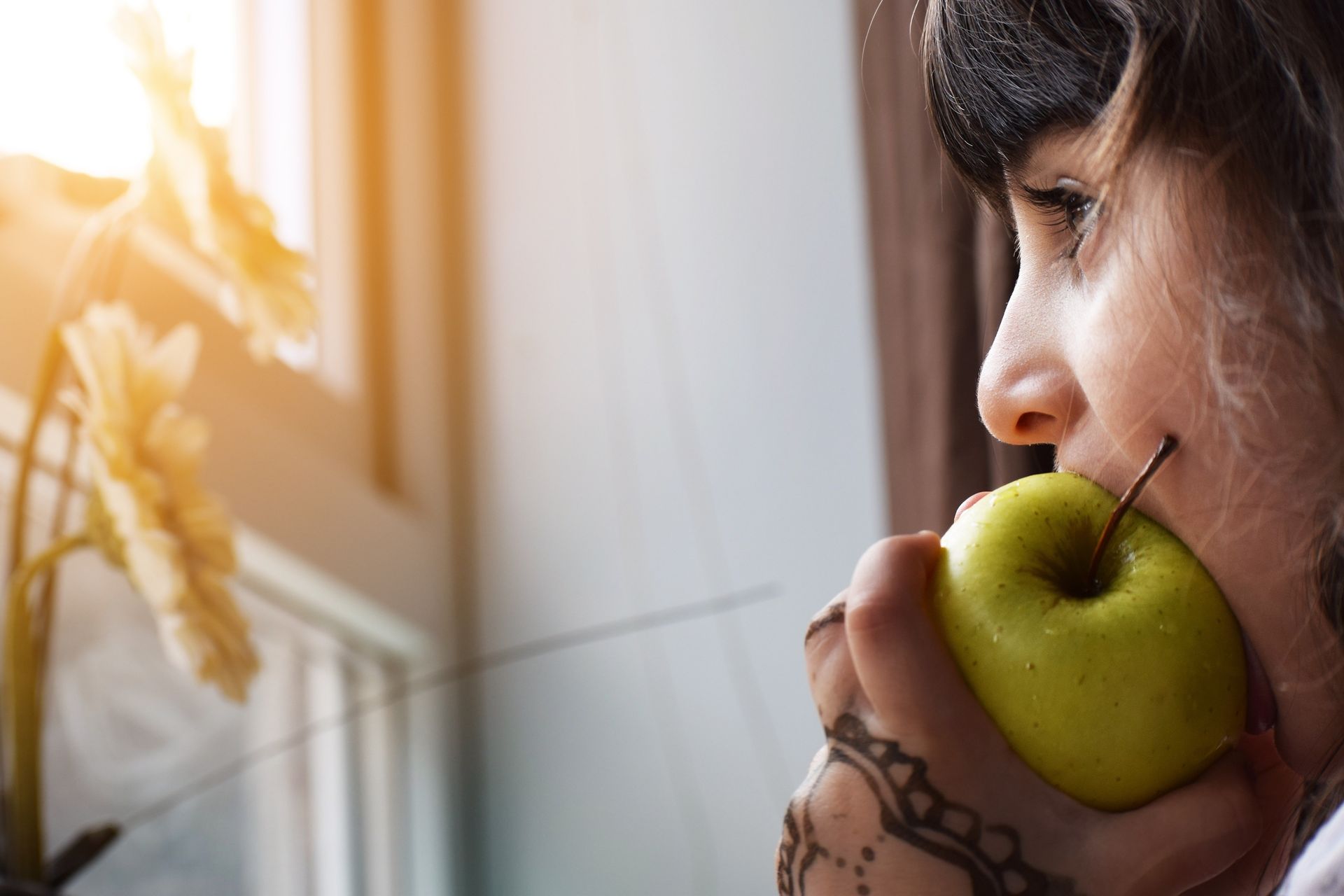 Girl biting a green apple by Khamkhor for Denture Doctor.
