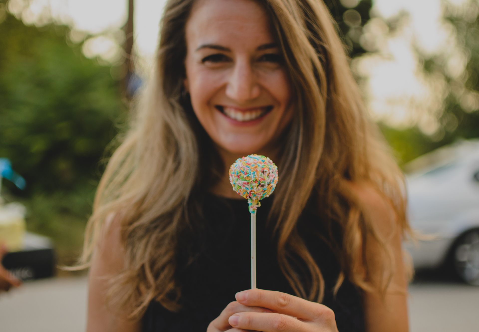 A girl holding a lollipop while showing a beautiful smile.
