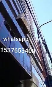 Un alto edificio de cristal, con un número de contacto de WhatsApp: 1537653400, contra un cielo azul.