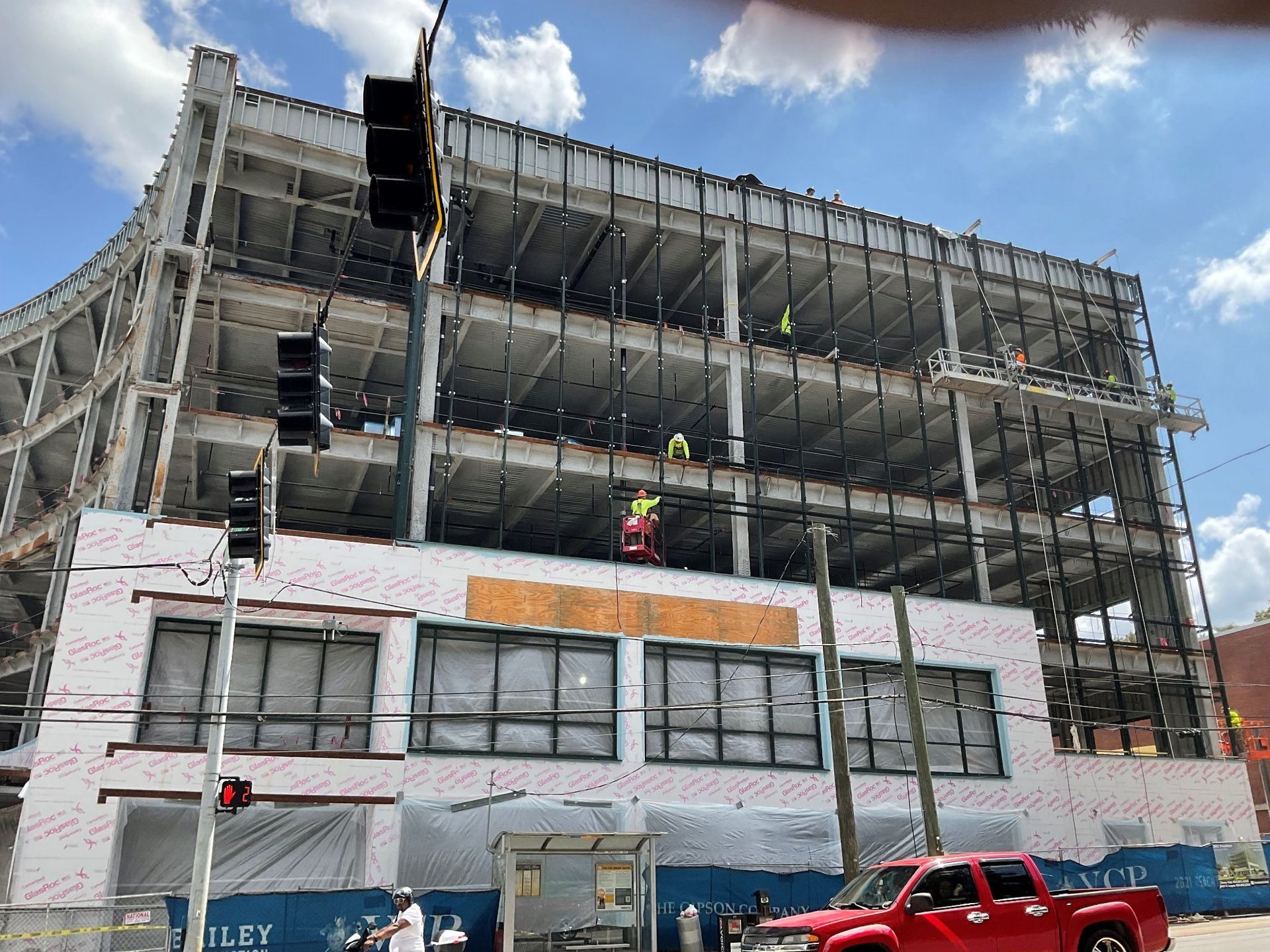 A red truck is parked in front of a building under construction.