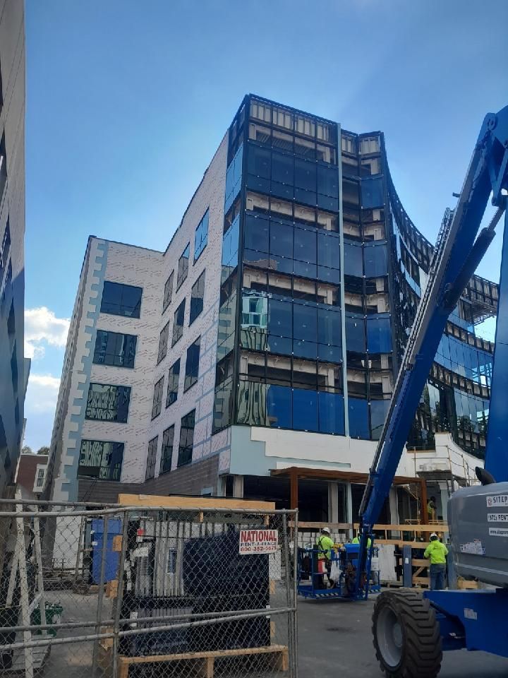 A large building under construction with a blue crane in front of it.