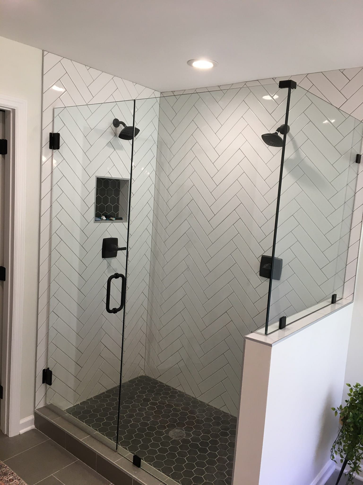 A bathroom with a walk in shower with a herringbone pattern on the wall.
