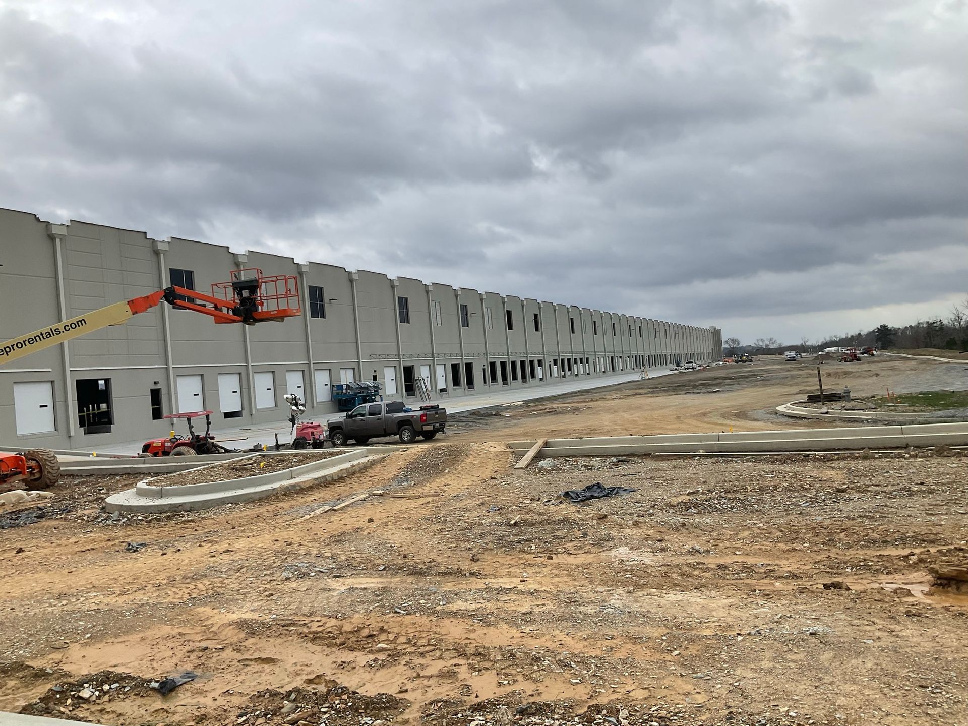 A large building is being built in the middle of a dirt field.