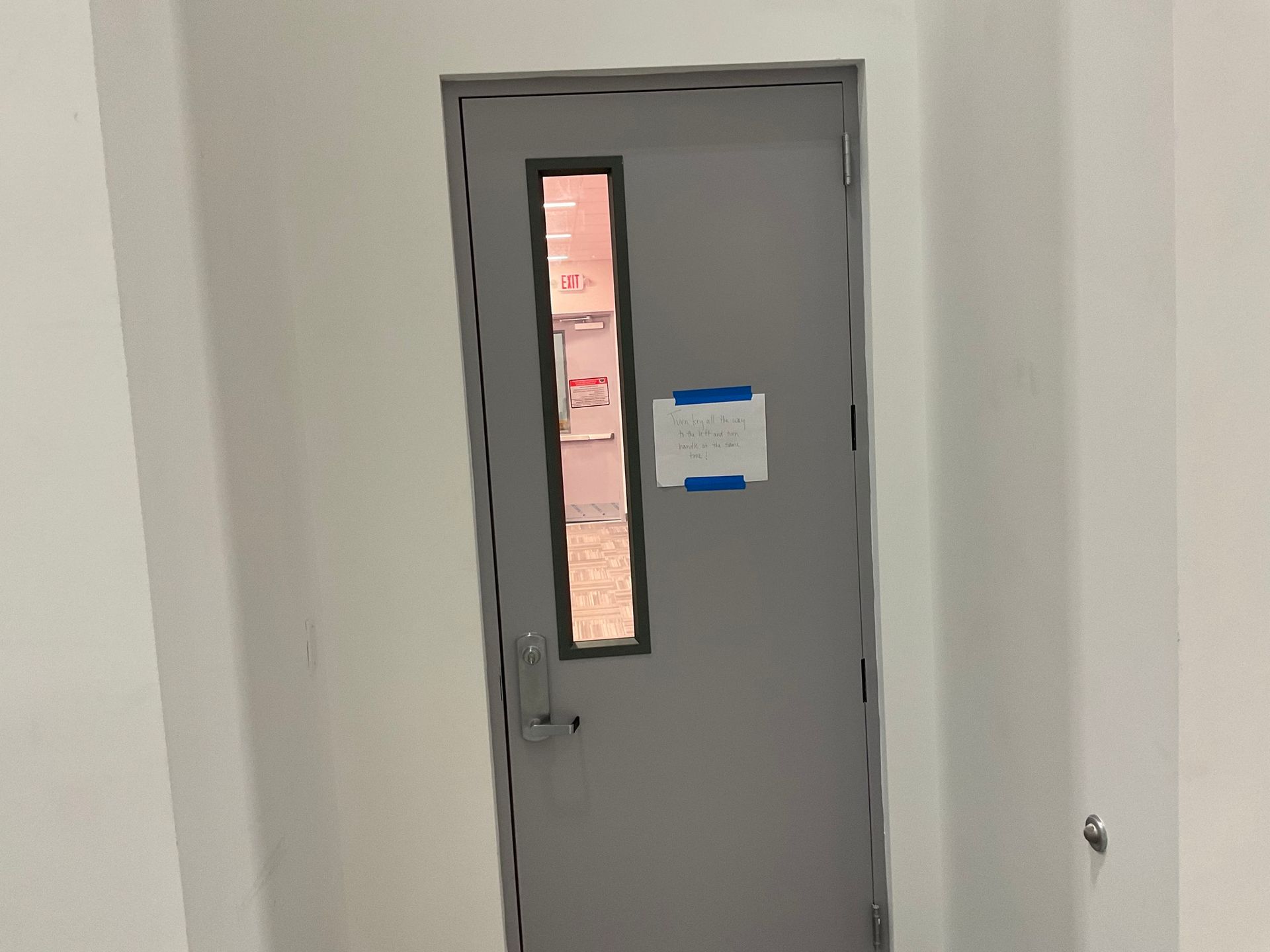 A door with a window in a room with a white wall.