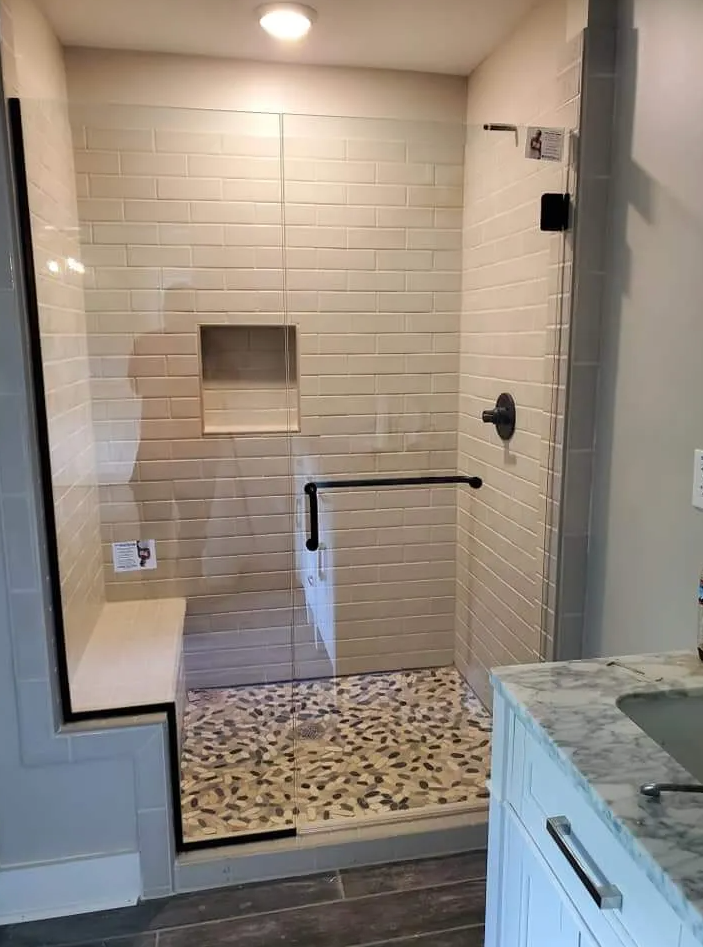 A bathroom with a walk in shower and a sink.