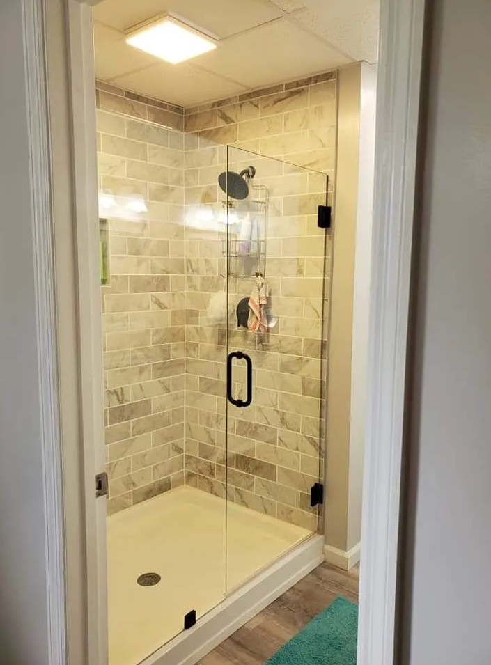 A bathroom with a walk in shower with a glass door.