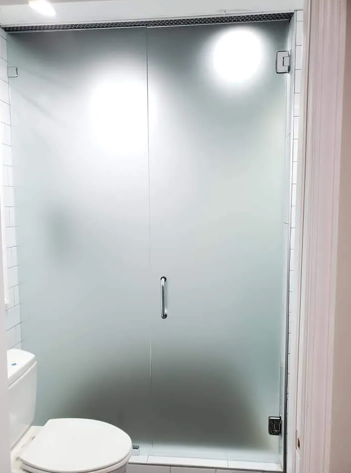 A bathroom with a toilet and a glass shower door.