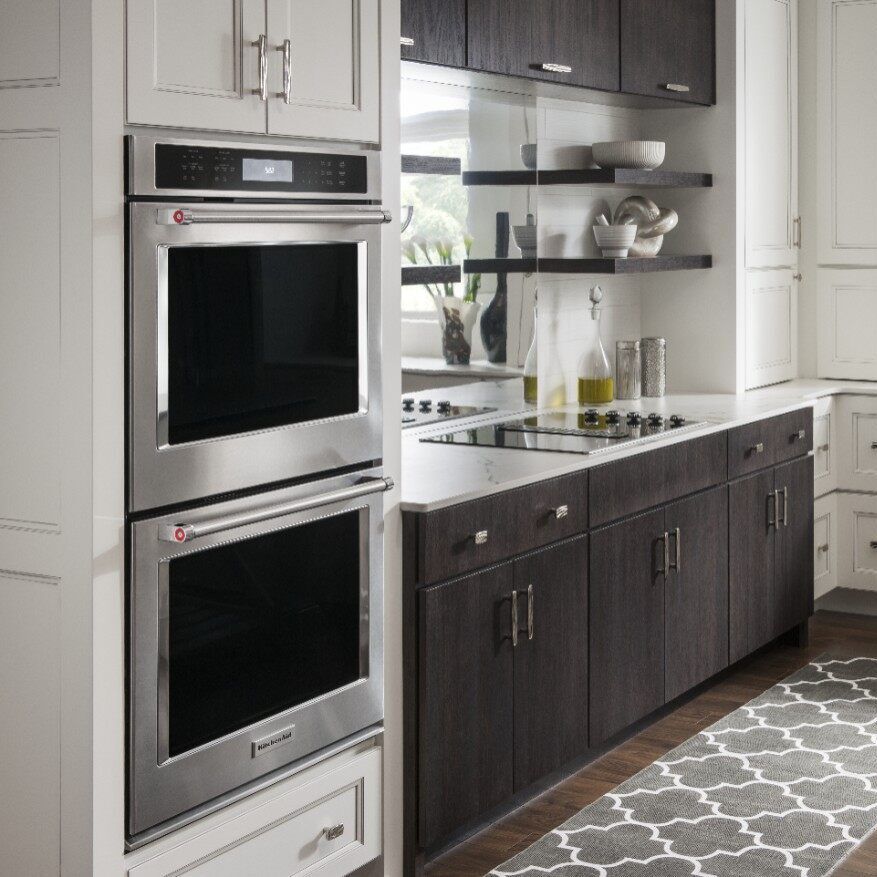 Stainless steel double oven in a modern kitchen with dark and white cabinets.