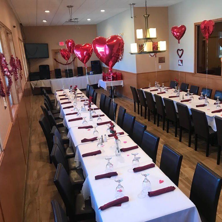 A long dining room with tables and chairs and balloons in the shape of hearts