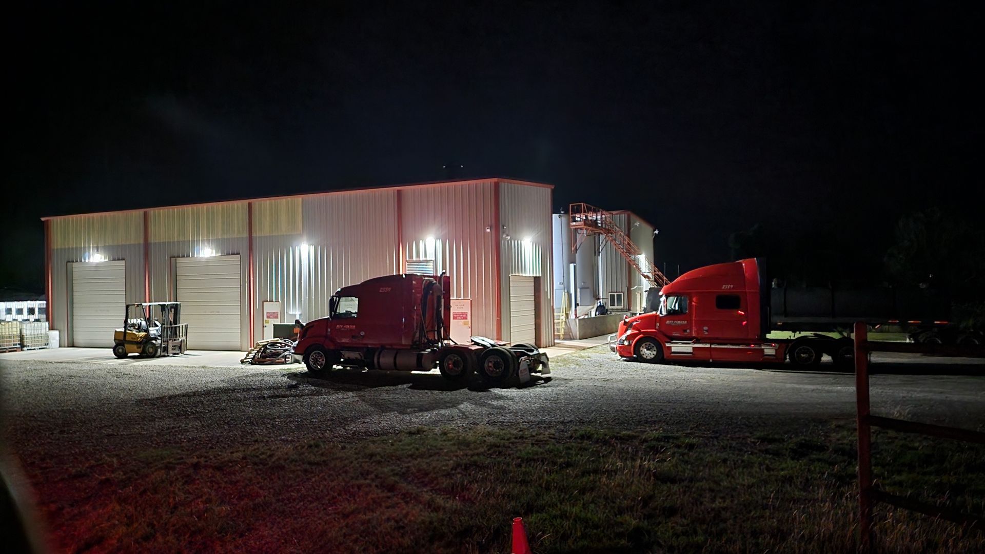 A red semi truck is parked in front of a building at night.