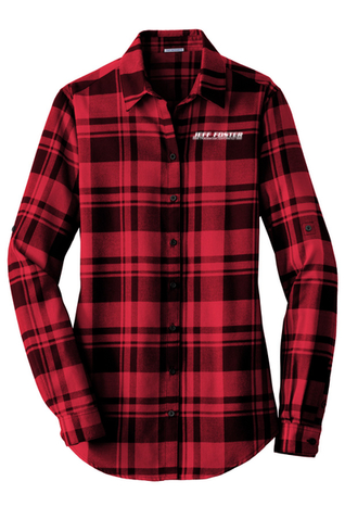 A woman is wearing a red plaid shirt with a logo on the front.