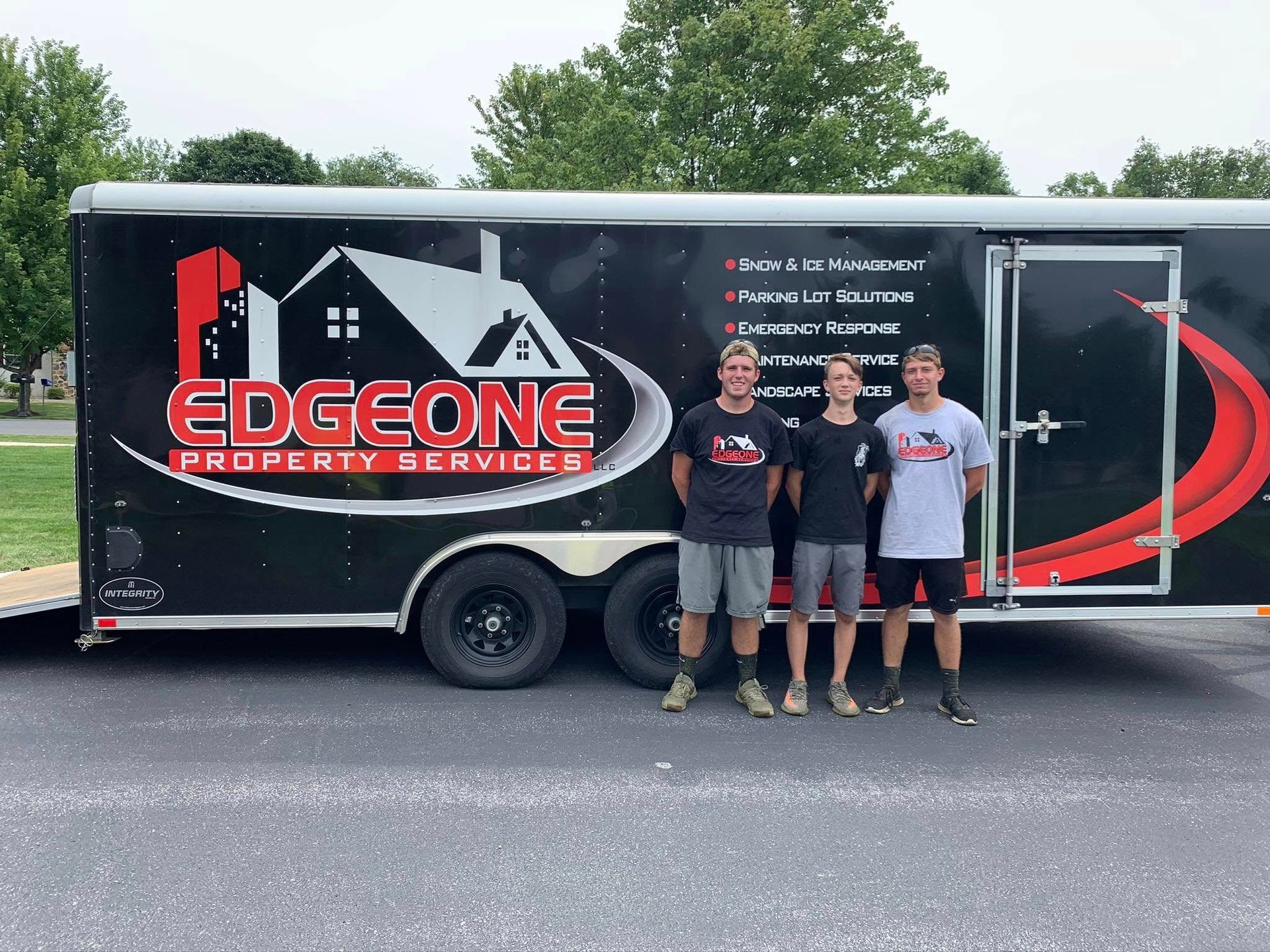 Three people stand in front of a trailer with 