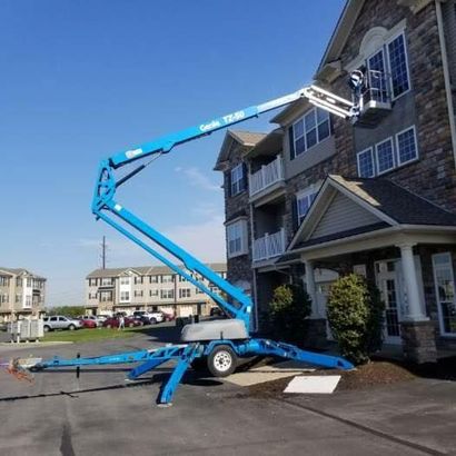 A man is cleaning the side of a house with a pressure washer.
