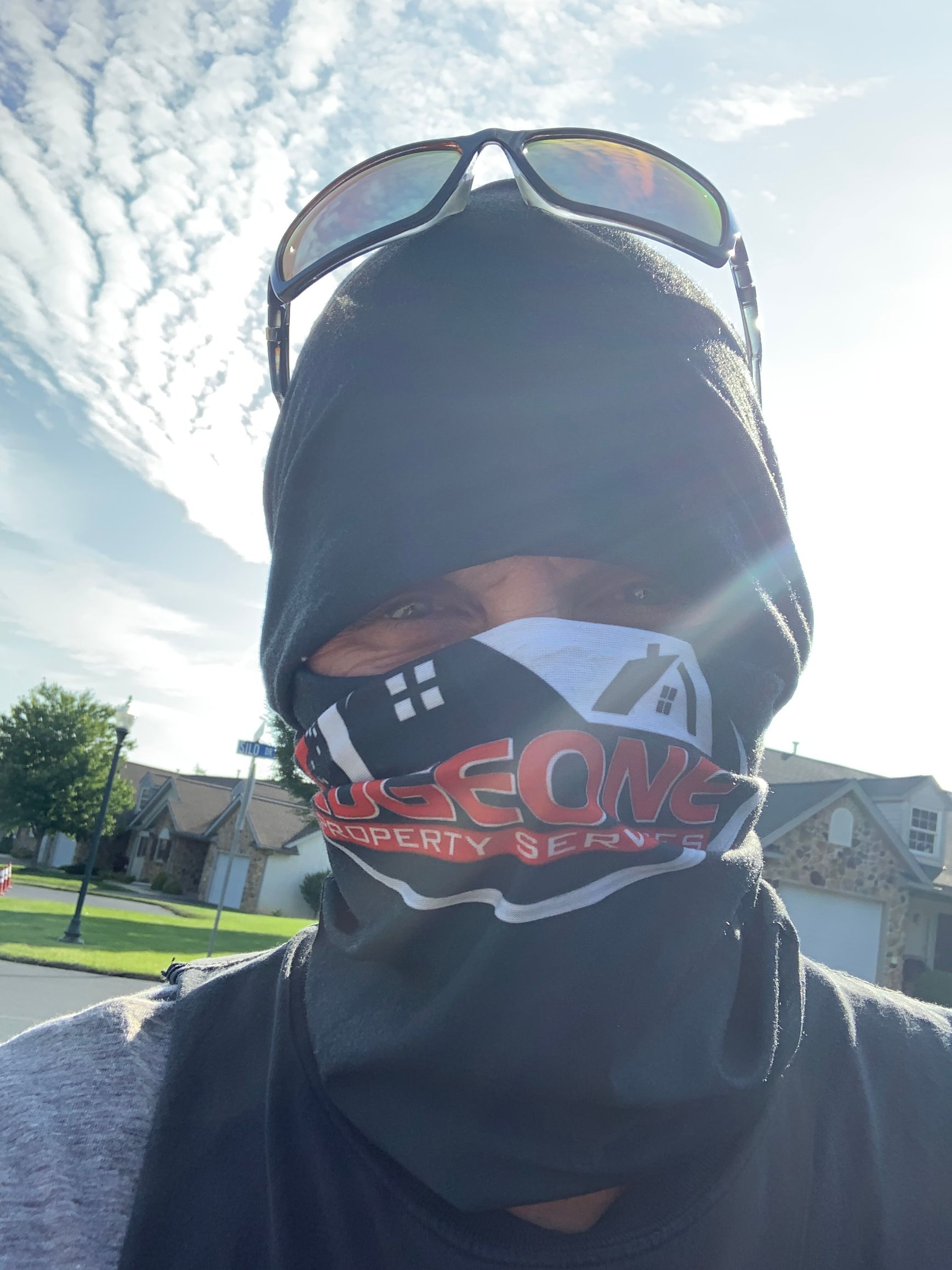 Person wearing sunglasses and a face covering outdoors.