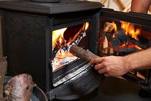 Placing Wood on the Stove Burner | Ashland, MA | Lunkers Outfitters