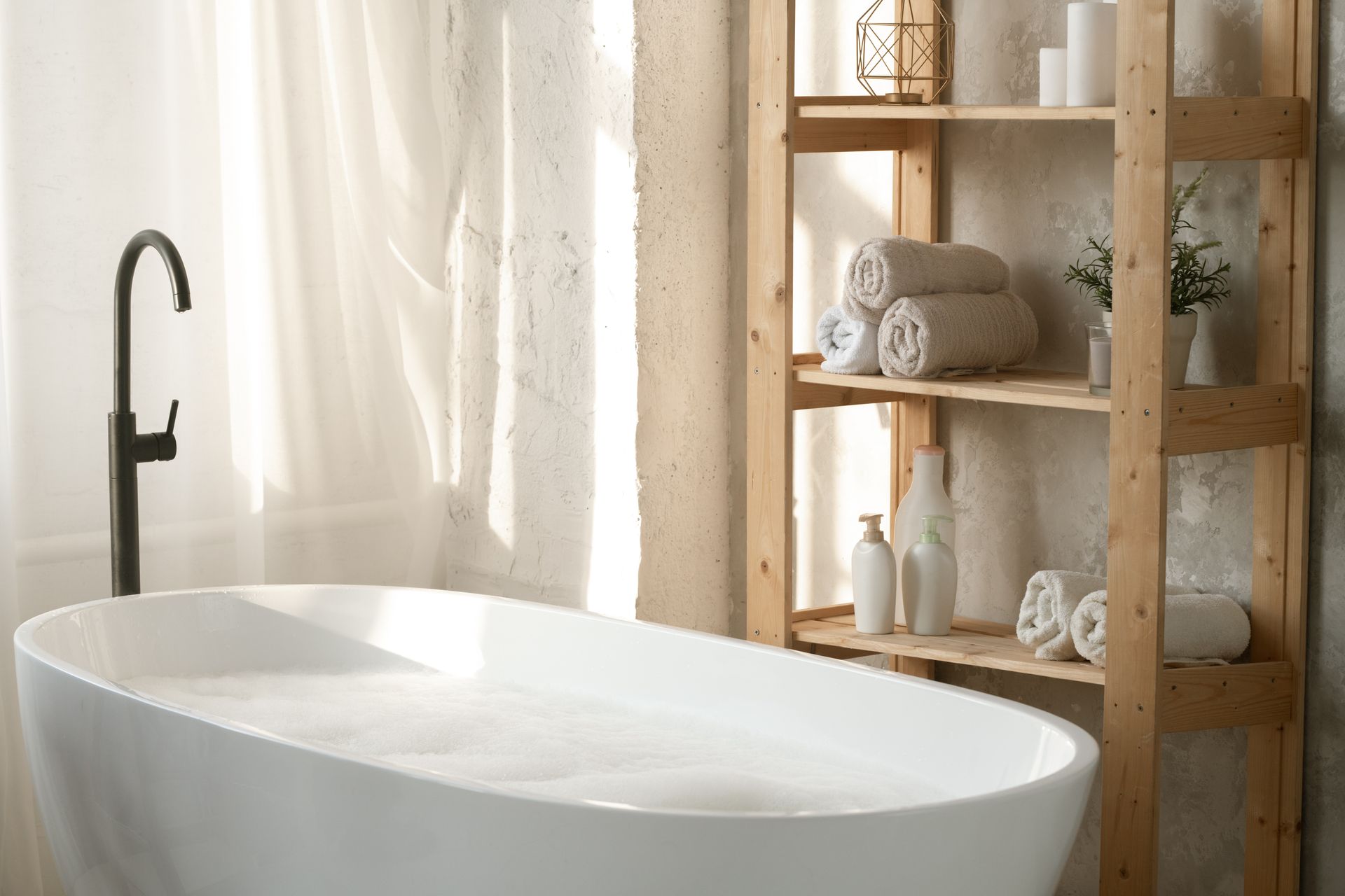 Large porcelain white bathtub filled with water and foam.