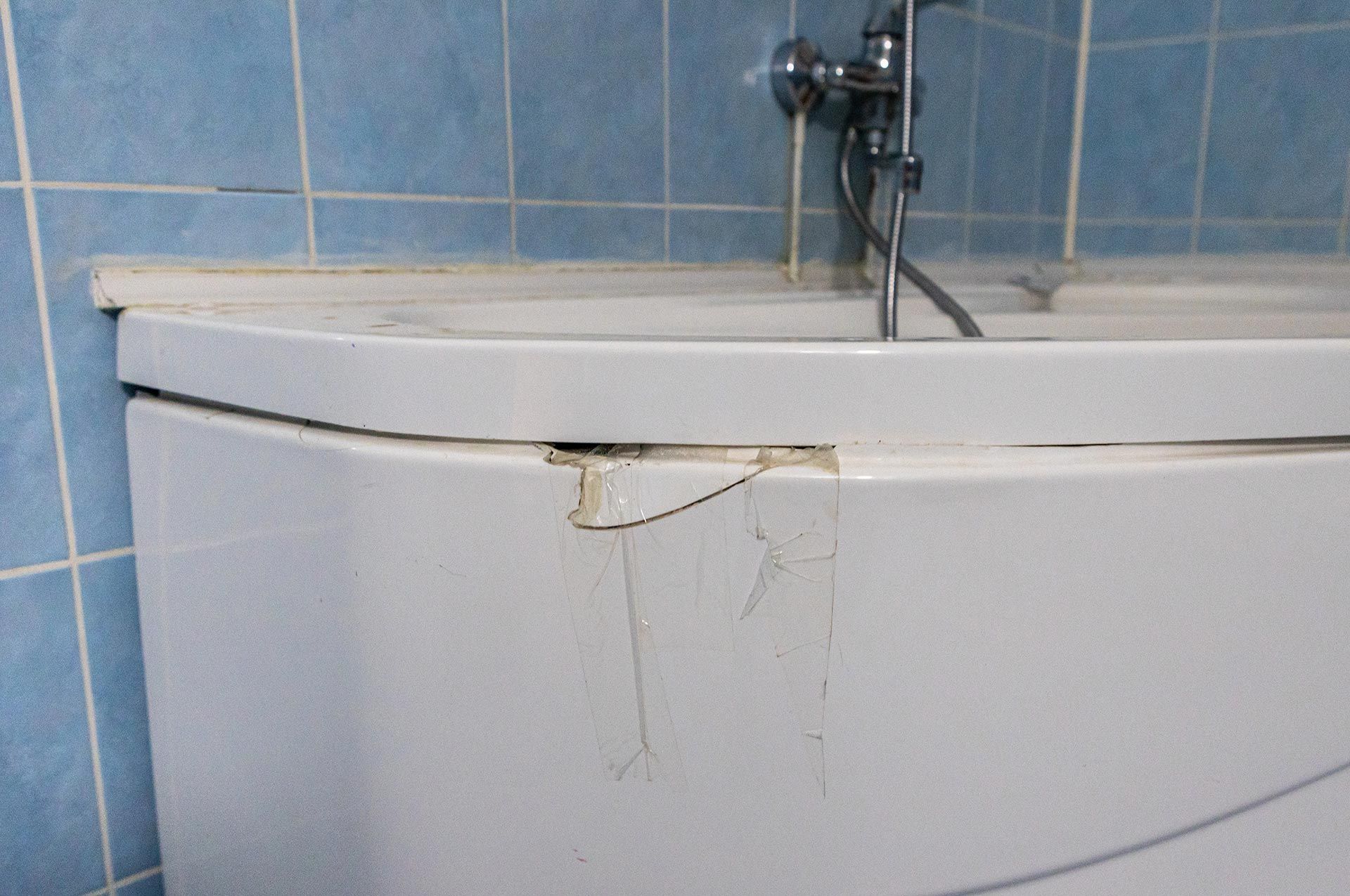 An old bathtub with a large and big chipped section.