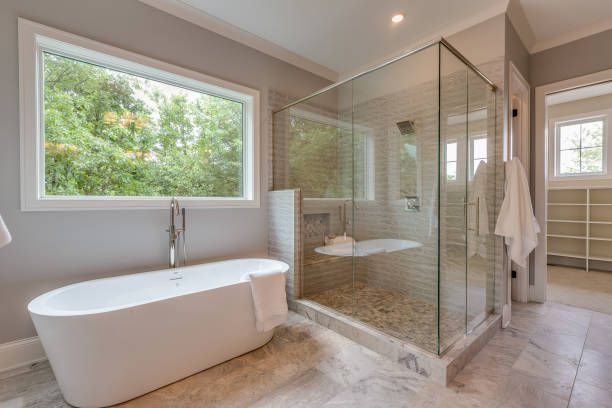 Large glass shower and free-standing bathtub in a modern bathroom.
